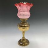 A late19th/early 20th century brass oil lamp, the frilled cranberry glass shade etched with floral