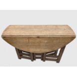 A light oak Cotswolds style gateleg supper table, the oval twin flap top raised on narrow