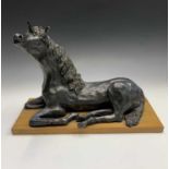 A ceramic sculpture of a unicorn, modelled in a recumbent pose with black finish, indistinctly