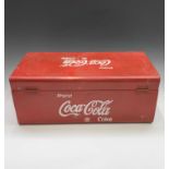 A large red painted tin cool box with handle, with raised lettering 'Coca Cola'. Width 59.5cm.