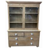 A pine bookcase, with a pair of glazed doors above two short and two long drawers, height 196cm,