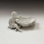 A Dresden porcelain dish, 20th century, white glazed, mounted with a cherub, with rococo moulded and
