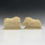 A pair of carved alabaster recumbent lion ornaments. Height 10cm, width 14cm.