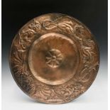 An Arts and Crafts copper charger, with a border of dragons on a hammered ground and central