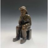 A carved wood model of Jersey Fisherman, seated, signed to base with fish motif. Height 30cm.