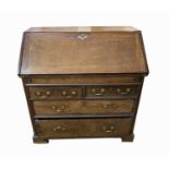 A George III oak bureau, the fall front enclosing a fitted interior, above two short and three