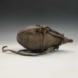 A tribal water carrier and cover of gourd shape, with woven cover and leather straps. Height 37cm.