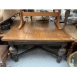 An oak draw leaf dining table, circa 1920's, with large bulbous supports on an X frame stretcher,