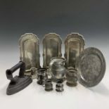 Three pewter candle wall sconces, height 27cm, five pewter measures. a pewter plate and a flat iron.