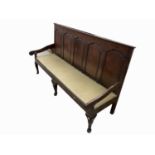 A George III oak settle, the back with five arched panels above a padded seat and cabriole legs,