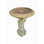 A reconstituted stone bird bath on cast tree trunk support. Height 63cm.