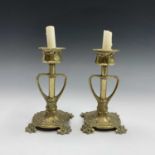A pair of Continental Art Nouveau brass candlesticks, the stems with whiplash handles, on leaf and