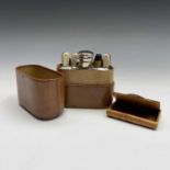 An early 20th century leather cased travel set, containing a spirit flask with two detachable