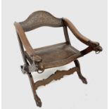 An Italian walnut X-frame low armchair, early 20th century, the arched top rail carved with a