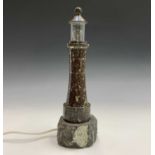 A Cornish serpentine table lamp, modelled as a lighthouse on a rocky base Height 35cm.