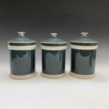 A set of three grey glazed apothecary jars and covers, circa 1900, of plain cylindrical form. Height