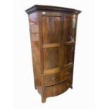 A mahogany bow front wardrobe, early 20th century, with a pair of twin panelled doors above a