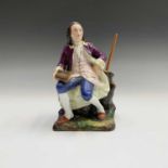 A 19th century French porcelain figural pen holder, modelled as a seated bewigged man holding a book