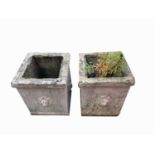 A pair of reconstituted stone square section planters with lion mask decoration. Height 46cm.