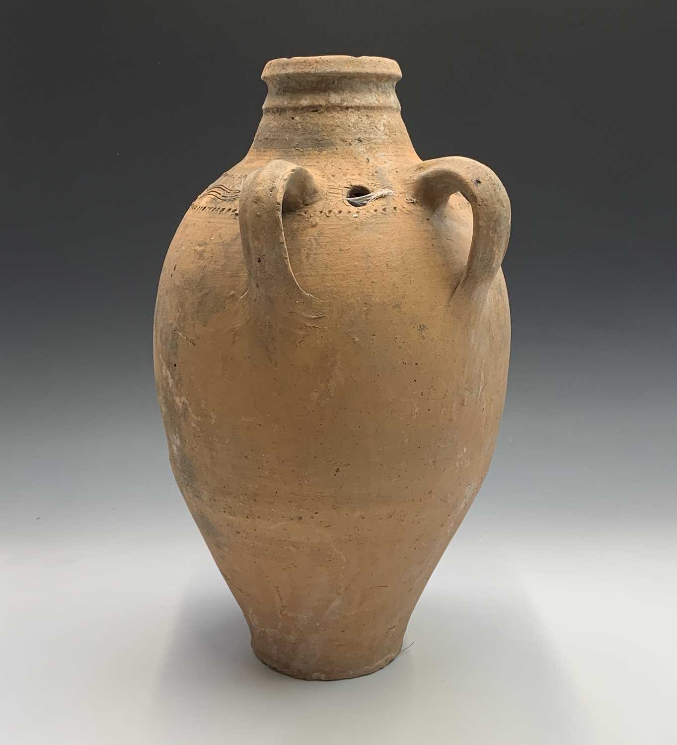 A terracotta vessel with twin handles, incised and impressed banded decoration. Height 55cm.