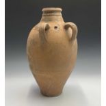 A terracotta vessel with twin handles, incised and impressed banded decoration. Height 55cm.