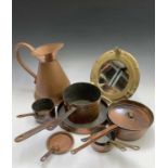 A Victorian copper frying pan, seven other copper pans, a copper jug and a brass porthole type
