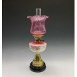 A Victorian oil lamp, with floral painted pink opaque glass reservoir and cranberry shade, overall