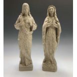 A pair of religious moulded plaster figures, depicting Christ and Mary with weathered stone