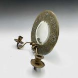 An Aesthetic movement brass circular wall mirror, circa 1880, with twin candle sconces, the broad