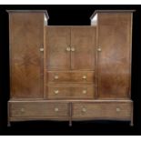 An Arts and Crafts walnut wardrobe, by Liberty & Co, the centre part fitted two doors enclosing