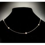 A platinum necklace with fine links and widely spaced pearls 56.5cm