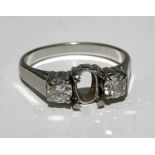 An 18ct white gold ring set with two diamonds but missing a central oval stone 5.2gm.Approx size: