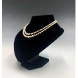 A double-strand graduated pearl necklace with large oval diamond-set white gold clasp. The largest