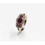 An Edwardian Chester hallmarked 18ct gold three stone ruby ring with a margin of diamonds.Approx