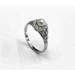 A refined white gold ring with a pearl and diamond target setting flanked by pierced diamond-set