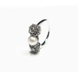 An exquisite white gold ring set a central 6.63mm pearl with a diamond cluster to each side.Approx