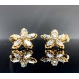 A pair of diamond flowerhead earrings each has five navette petals and a brilliant-cut stamen. Dia