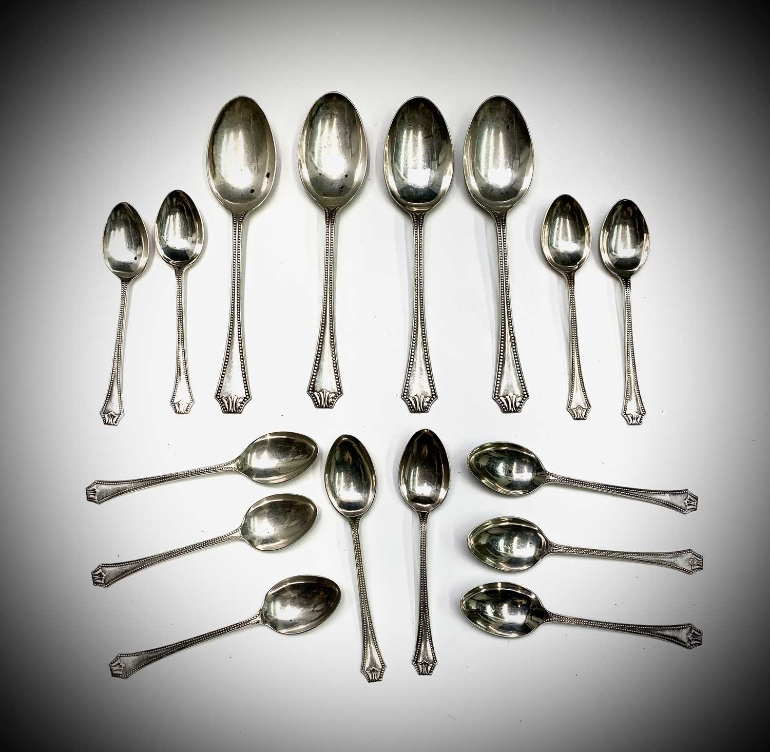 A set of twelve beaded silver teaspoons and four matching dessert spoons by Wilmot Manufacturing
