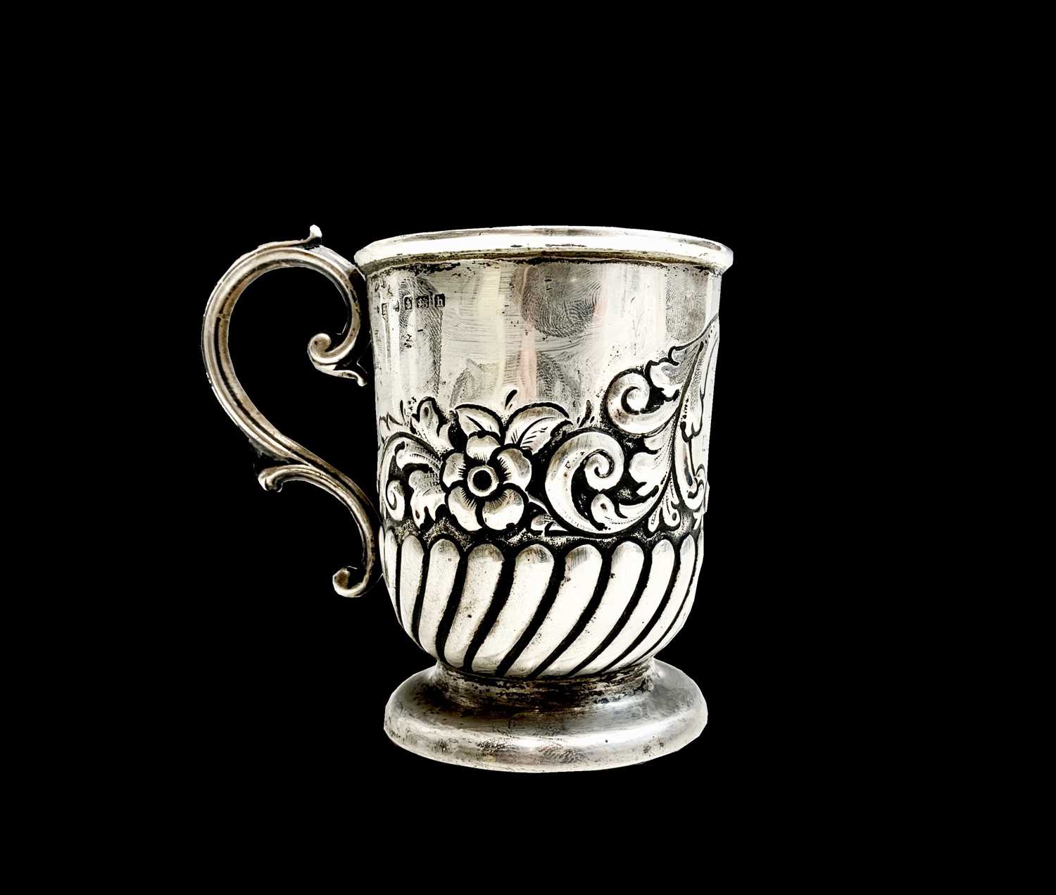 An Edwardian silver christening mug, half spiral fluted and embossed with flowers and scrolls.