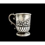 An Edwardian silver christening mug, half spiral fluted and embossed with flowers and scrolls.