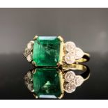 An impressive emerald and diamond ring, the principle stone is emerald cut with a weight of