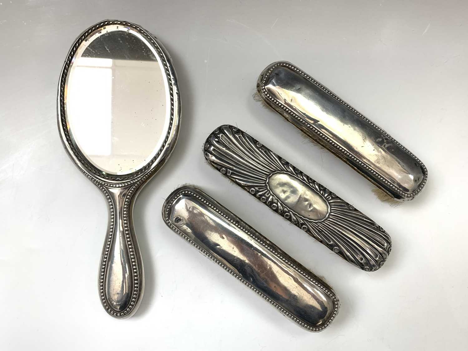 A silver-mounted mirror and three silver-mounted brushes