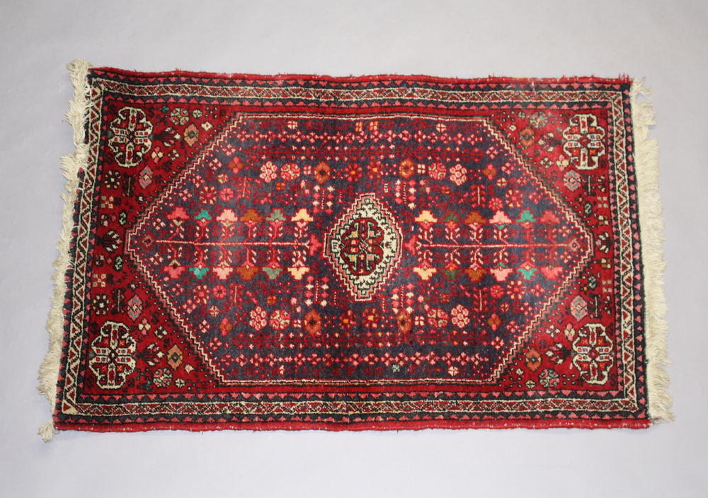 A red and blue ground Persian rug with diamond shaped central medallion 99cm x 60cmSome wear to