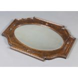 An Edwardian oval bevelled plate wall mirror contained in a shaped oak frame with geometric