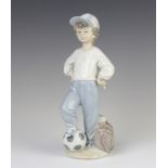 A Lladro Rotary International figure of a young boy with his football and kit bag 21cm