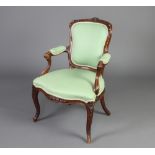 A French 19th/20th Century carved walnut open arm salon chair, the seat and back upholstered in