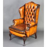 A Georgian style winged armchair upholstered in brown buttoned leather, raised on cabriole