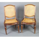 A pair of 18th Century French carved walnut chairs with woven cane seats and backs raised on