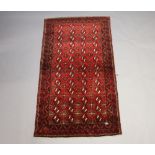 An Afghan red and white ground rug with 56 stylised medallions to the centre within a multi row