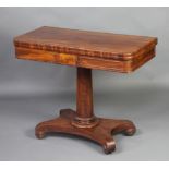 A William IV crossbanded mahogany D shaped card table raised on a turned column and triform base